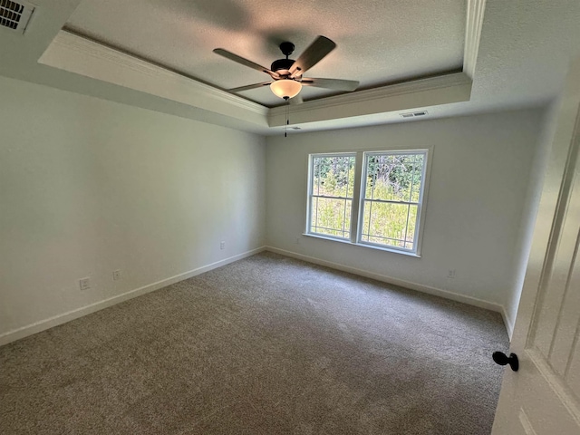 carpeted empty room featuring a raised ceiling, visible vents, ornamental molding, a textured ceiling, and baseboards