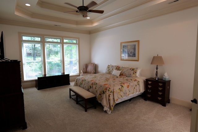 bedroom with a raised ceiling, light carpet, and multiple windows