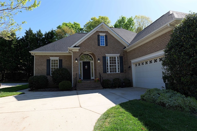 traditional-style house with driveway, a shingled roof, a garage, and brick siding