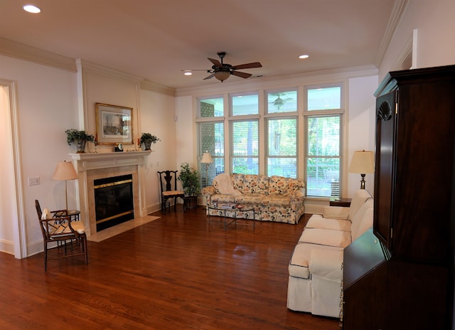 living area with dark wood-style floors, recessed lighting, ornamental molding, a fireplace with flush hearth, and ceiling fan