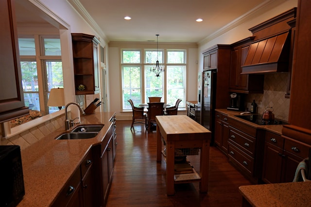 kitchen featuring dark wood-style flooring, pendant lighting, crown molding, a sink, and black appliances