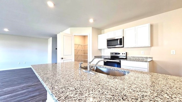 kitchen featuring dark wood-type flooring, sink, appliances with stainless steel finishes, light stone counters, and white cabinetry