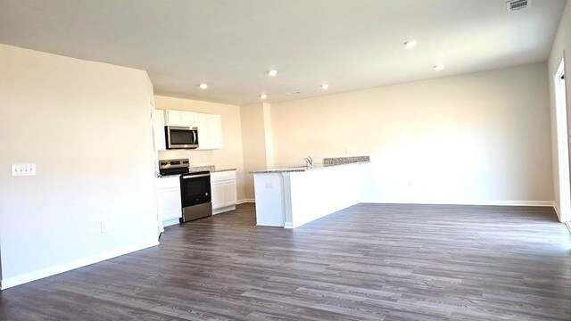 kitchen featuring dark wood-type flooring, light stone counters, kitchen peninsula, white cabinets, and appliances with stainless steel finishes