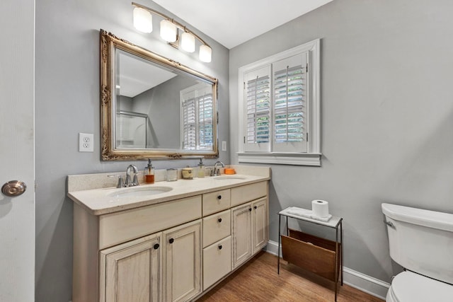 bathroom featuring hardwood / wood-style floors, toilet, double sink, and large vanity