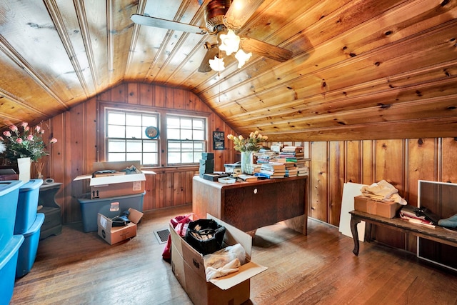 home office featuring wooden walls, wood-type flooring, ceiling fan, and vaulted ceiling