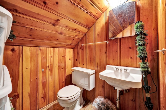 bathroom with wood walls, toilet, and vaulted ceiling