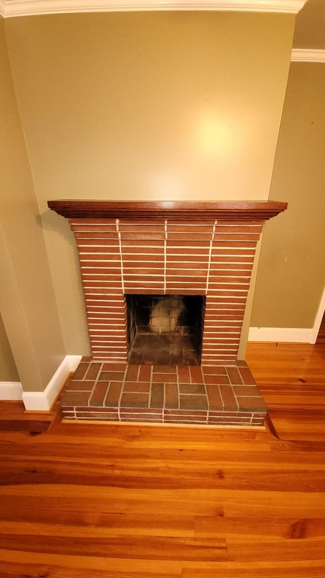 room details featuring crown molding, wood-type flooring, and a brick fireplace