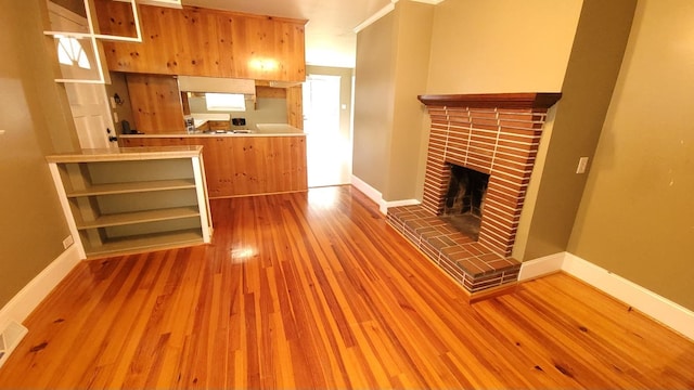 unfurnished living room featuring hardwood / wood-style floors and a brick fireplace