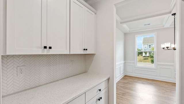 interior space with decorative backsplash, light hardwood / wood-style floors, white cabinetry, light stone counters, and crown molding