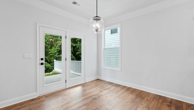 unfurnished room featuring wood-type flooring, crown molding, and a wealth of natural light