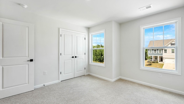 unfurnished bedroom with light carpet and a closet