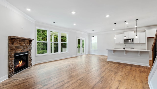 unfurnished living room featuring a stone fireplace, plenty of natural light, and light hardwood / wood-style floors