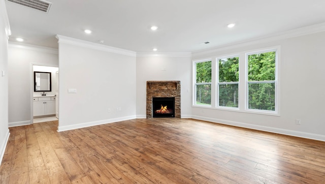 unfurnished living room with light wood-type flooring, a fireplace, sink, and crown molding