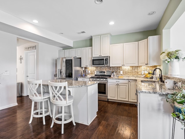 kitchen featuring a kitchen island, appliances with stainless steel finishes, dark hardwood / wood-style floors, a breakfast bar, and sink