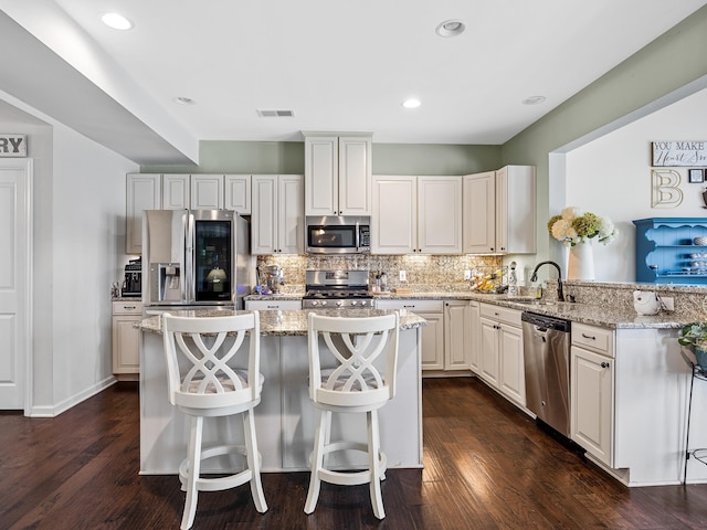 kitchen featuring stainless steel appliances, dark hardwood / wood-style floors, a breakfast bar, and a kitchen island