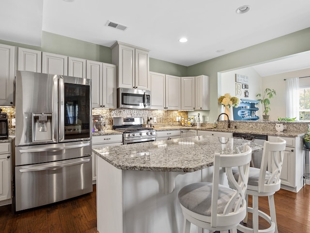 kitchen featuring dark hardwood / wood-style floors, tasteful backsplash, a kitchen island, and appliances with stainless steel finishes