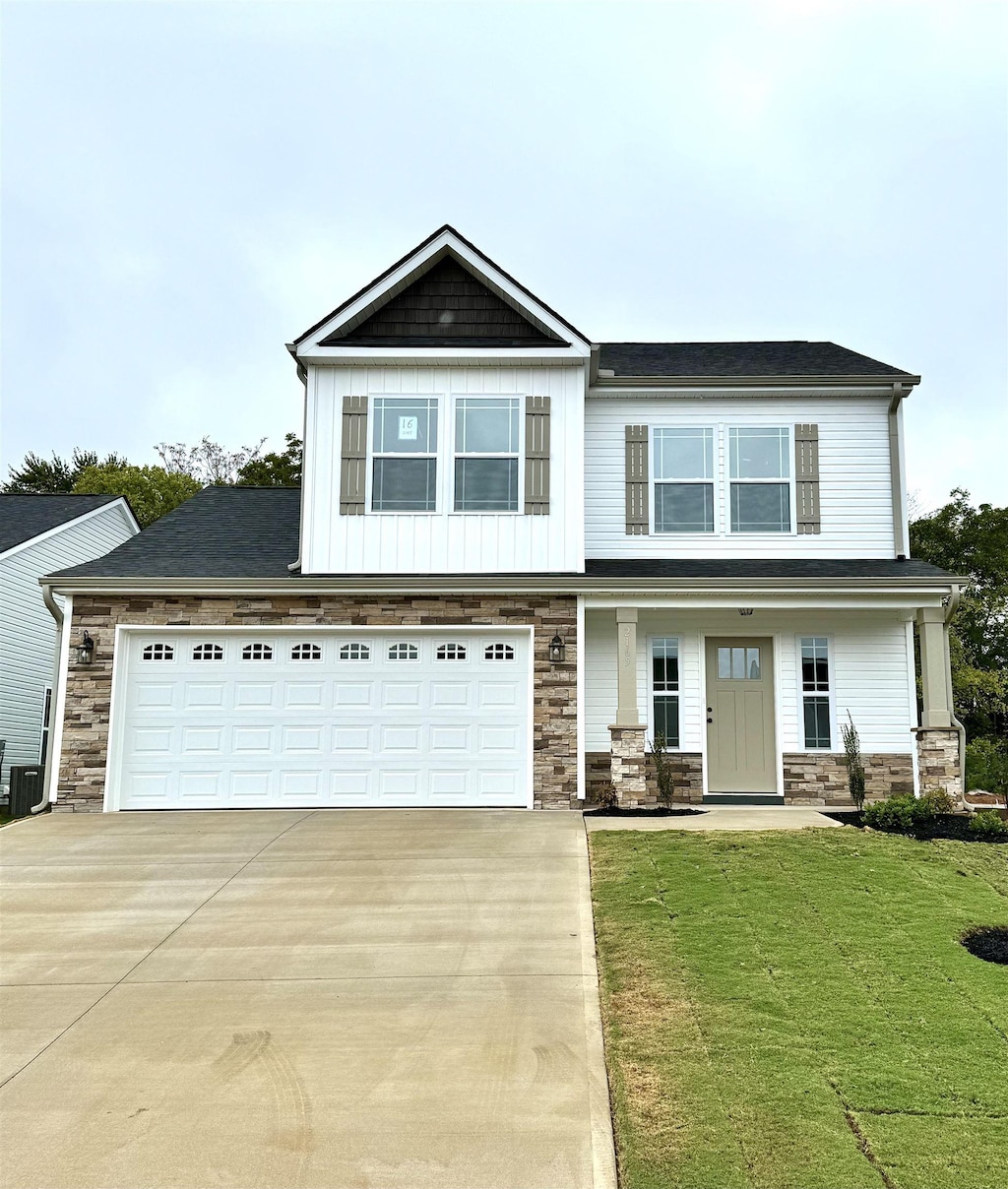 view of front of property with a garage, a porch, central AC, and a front lawn