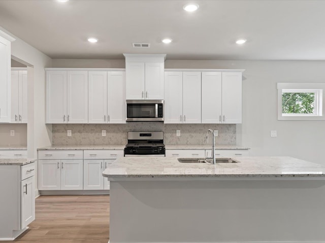 kitchen featuring white cabinets, stainless steel appliances, light stone counters, and sink