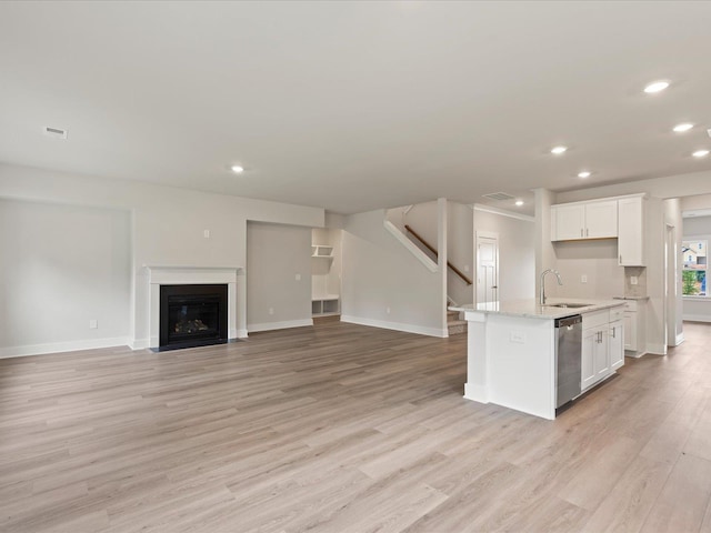 kitchen featuring white cabinetry, dishwasher, an island with sink, and sink