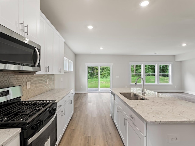 kitchen featuring a kitchen island with sink, sink, white cabinets, and appliances with stainless steel finishes