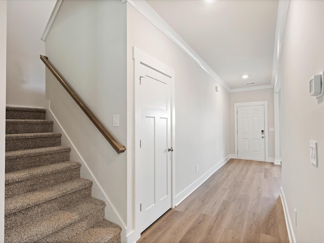 hall with light hardwood / wood-style floors and crown molding