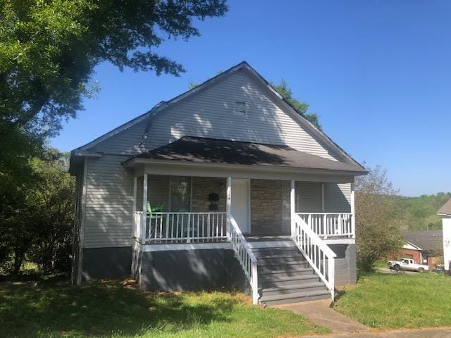 bungalow with covered porch and a front lawn