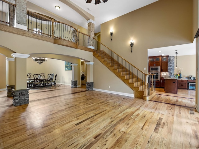 interior space with decorative columns, light hardwood / wood-style floors, and a high ceiling