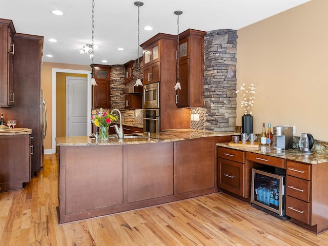 kitchen featuring kitchen peninsula, light wood-type flooring, light stone counters, pendant lighting, and wine cooler