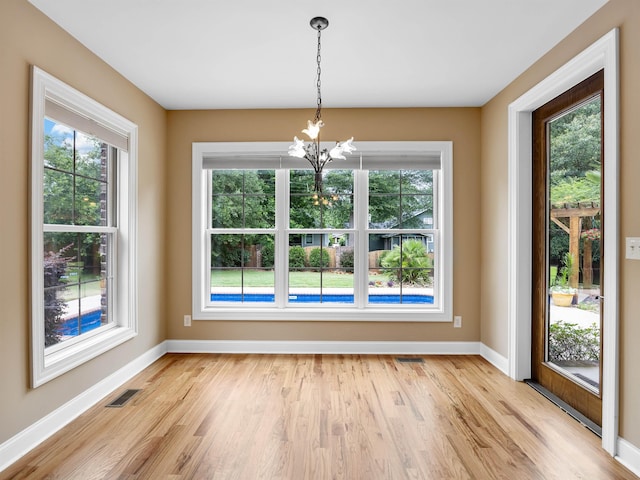 unfurnished dining area with light hardwood / wood-style floors and a chandelier