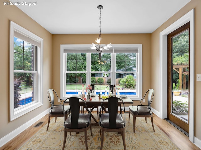 dining room with light wood-type flooring and an inviting chandelier