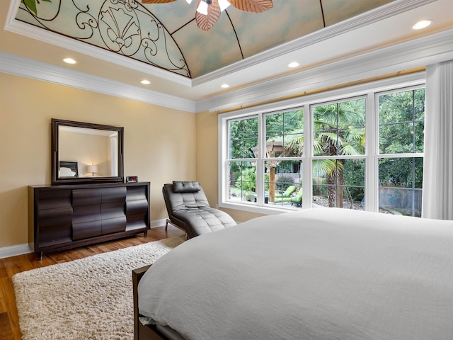 bedroom with hardwood / wood-style flooring, ceiling fan, crown molding, and a tray ceiling