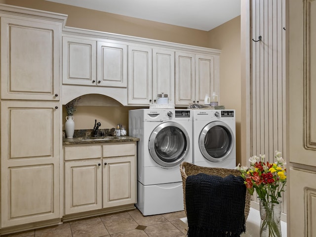 washroom with cabinets, light tile patterned floors, washer and clothes dryer, and sink