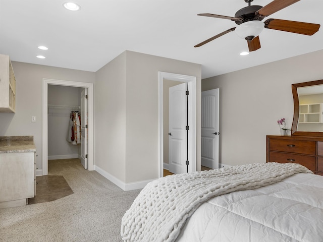 carpeted bedroom featuring a walk in closet, ceiling fan, and a closet