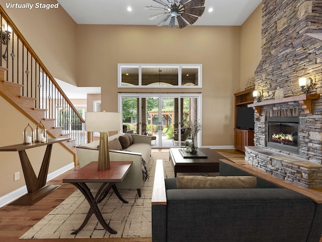 living room with hardwood / wood-style floors, a fireplace, a high ceiling, and french doors