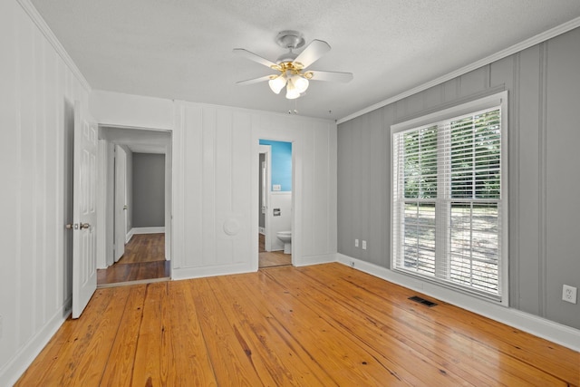 empty room with a textured ceiling, light hardwood / wood-style flooring, ceiling fan, and crown molding