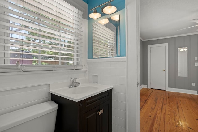 bathroom featuring hardwood / wood-style floors, vanity, toilet, ornamental molding, and tile walls