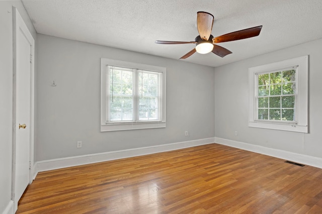 unfurnished room featuring plenty of natural light, ceiling fan, a textured ceiling, and light hardwood / wood-style flooring