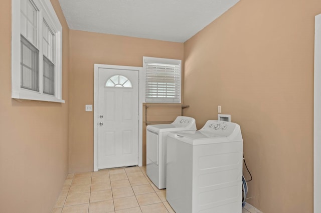 washroom with light tile patterned floors, washing machine and dryer, and a textured ceiling