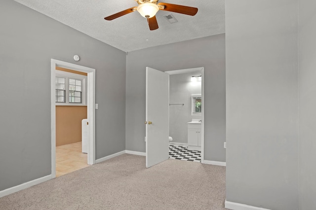 unfurnished bedroom with ensuite bathroom, ceiling fan, light colored carpet, and a textured ceiling