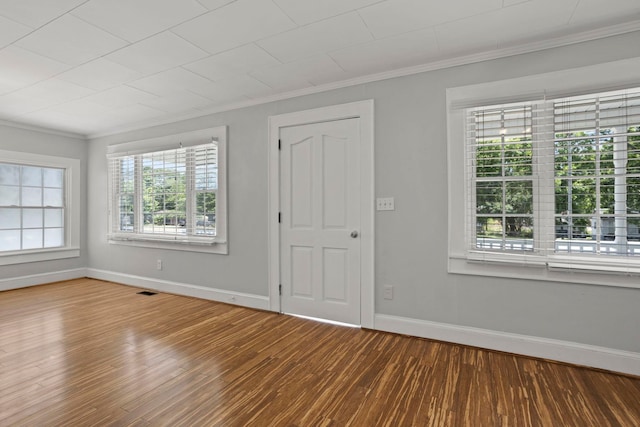 unfurnished room with hardwood / wood-style floors, ornamental molding, and a wealth of natural light