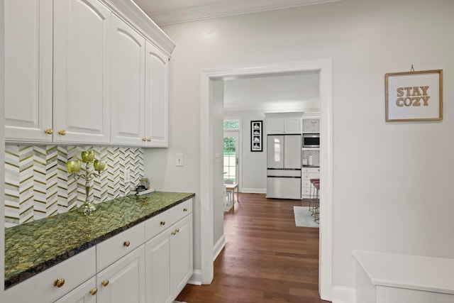 interior space with dark wood-style flooring, white cabinets, white fridge, tasteful backsplash, and stainless steel microwave