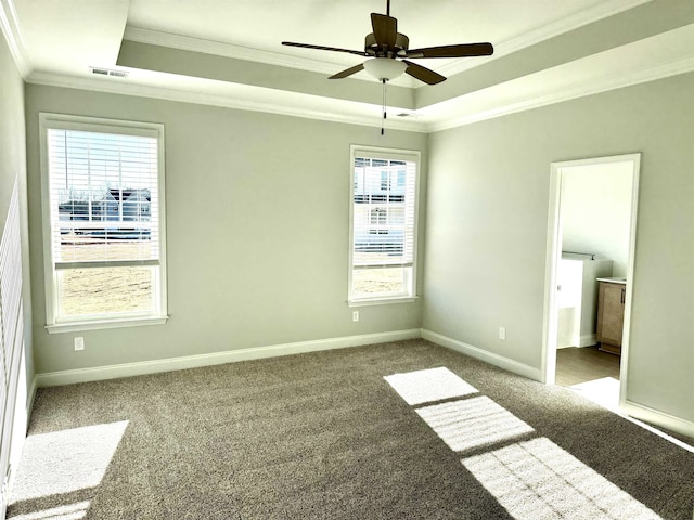 empty room featuring carpet flooring, ceiling fan, a raised ceiling, and ornamental molding