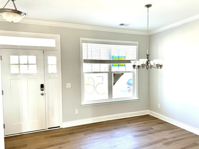 entryway featuring a notable chandelier, wood-type flooring, crown molding, and a wealth of natural light