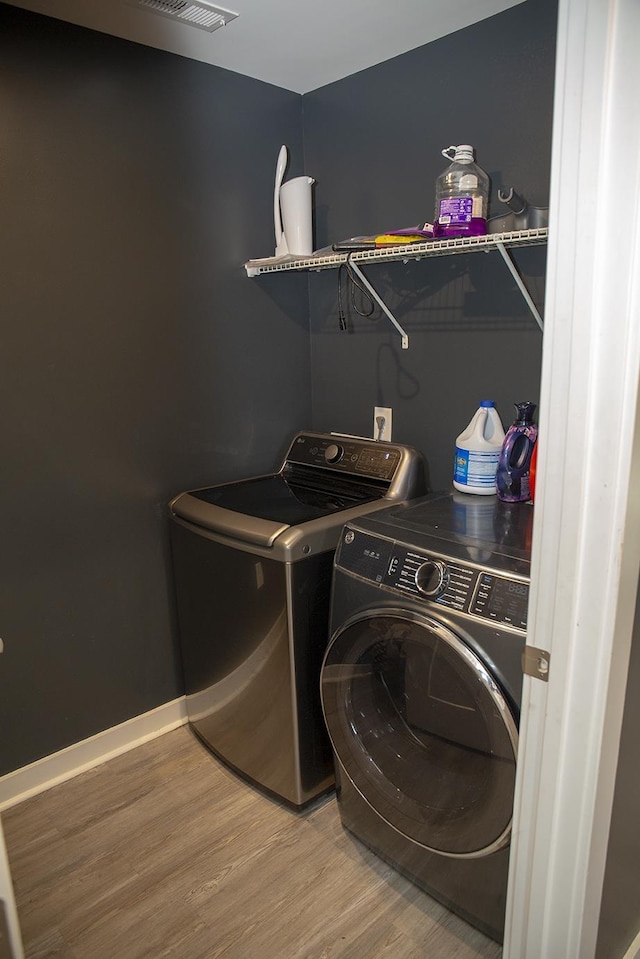 clothes washing area featuring washing machine and dryer and hardwood / wood-style flooring