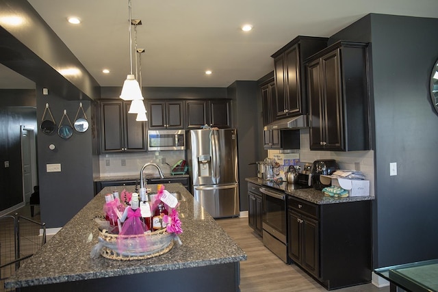 kitchen featuring a center island with sink, pendant lighting, stainless steel appliances, and tasteful backsplash