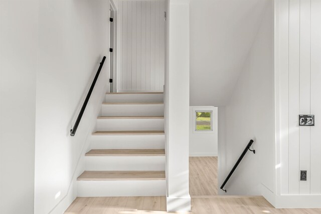 stairs with vaulted ceiling and hardwood / wood-style floors