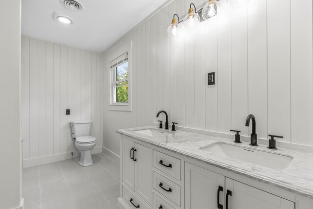 bathroom featuring vanity, tile patterned floors, wooden walls, and toilet