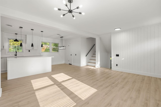 unfurnished living room featuring a chandelier and light hardwood / wood-style floors