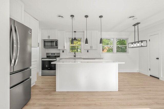 kitchen with white cabinetry, decorative light fixtures, a kitchen island, stainless steel appliances, and backsplash