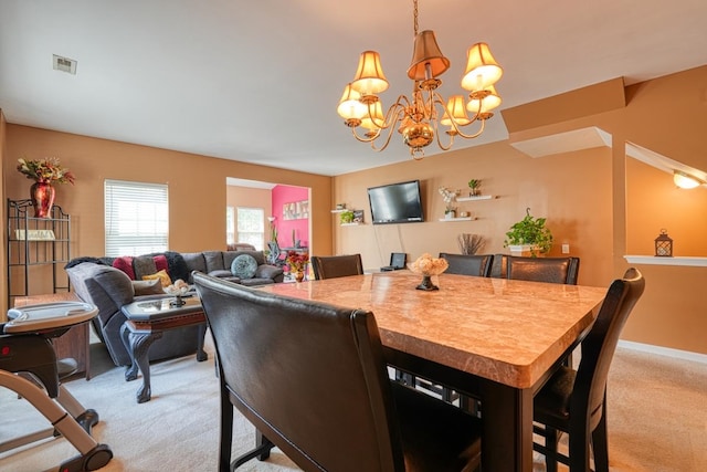 dining area with light carpet and a chandelier